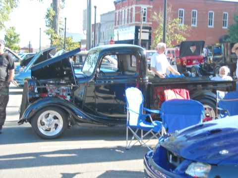 1979 Ford F-150 - A black pickup truck is parked at an outdoor event with its hood open.