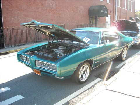 1979 Ford F-150 - A teal 1969 Pontiac GTO is displayed with its hood open, parked on a street next to another vehicle.