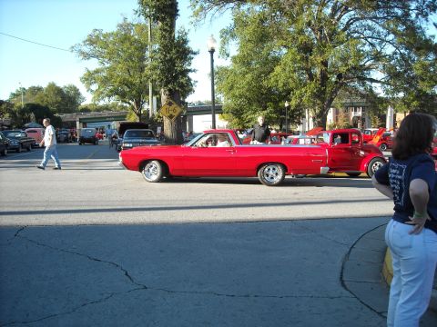 1979 Ford F-150 - A red pickup truck with a long bed is seen from the side at a car show, with other vehicles and spectators in the background.