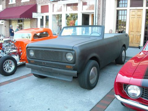 1979 Ford F-150 - A matte black International Scout II convertible is parked on a street next to other vehicles.