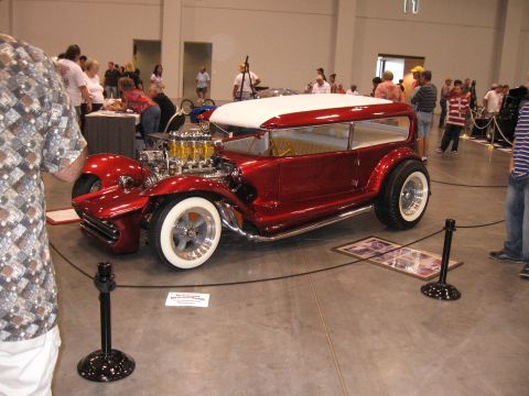 1968 Shelby GT500 - A highly customized hot rod with a prominent V8 engine is displayed indoors at a car show.