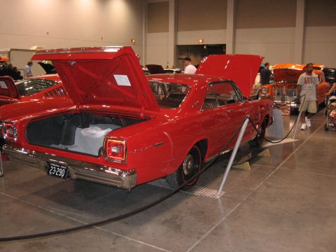 1968 Shelby GT500 - A red 1966 Ford Fairlane is displayed with its trunk and hood open at an indoor car show.