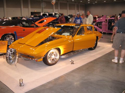 1968 Shelby GT500 - A yellow coupe, likely a 1963 Corvette, is displayed with its hood open at a car show.
