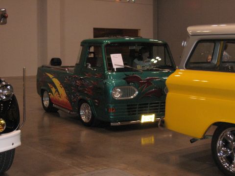 1968 Shelby GT500 - A green custom van with flame graphics is displayed next to a yellow vehicle at a car show.