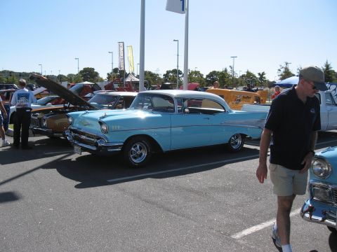 1968 Shelby GT500 - A light blue 1957 Chevrolet Bel Air coupe is displayed at a car show with multiple other vehicles present.