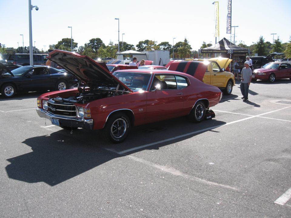 Red 1970 Chevelle SS with hood open, parked next to a yellow pickup truck