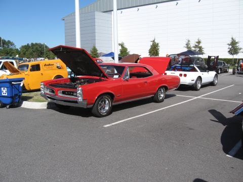 1968 Shelby GT500 - A red 1967 Pontiac GTO coupe is displayed with its hood open at a car show, alongside other vehicles.