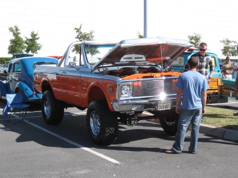 1968 Shelby GT500 - A lifted 1972 Chevrolet K5 Blazer is displayed with its hood open, next to a blue classic car.