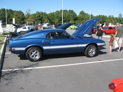 1968 Shelby GT500 - A blue 1969 Ford Mustang Mach 1 is displayed at an outdoor car show with its hood up.