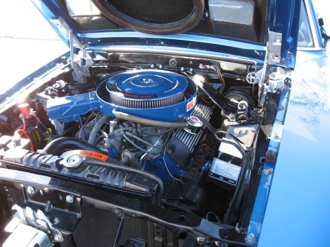 1968 Shelby GT500 - The engine bay of a blue 1968 Shelby GT500 is visible with the hood open, revealing the V8 engine and associated components.