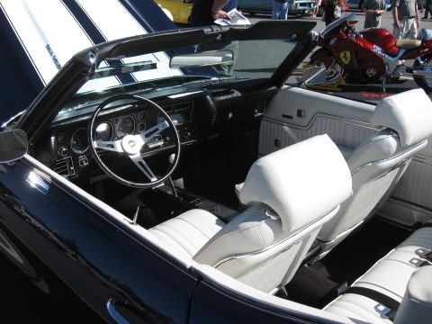 1968 Shelby GT500 - The interior of a dark blue convertible with white seats and racing stripes on the hood is shown at a car show.