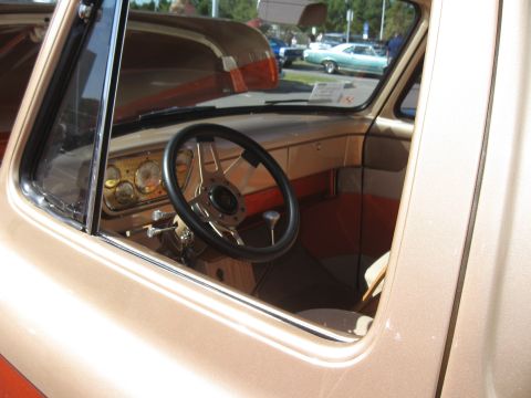 1968 Shelby GT500 - The interior of a custom classic car features a tan dashboard, orange seats, and a sporty steering wheel.