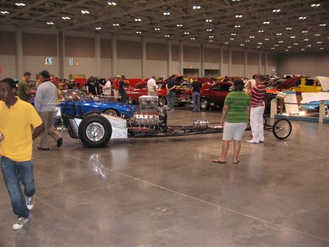 1968 Shelby GT500 - A dragster chassis with a powerful engine is showcased at an indoor car show event.