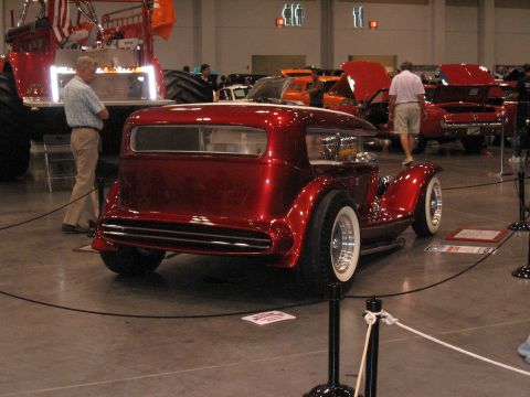 1968 Shelby GT500 - A custom hot rod is displayed indoors, with other vehicles and attendees in the background.