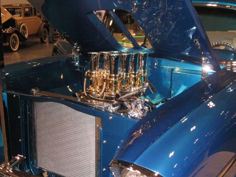 1968 Shelby GT500 - A blue hot rod's engine bay is displayed with multiple carburetors and chrome accents.