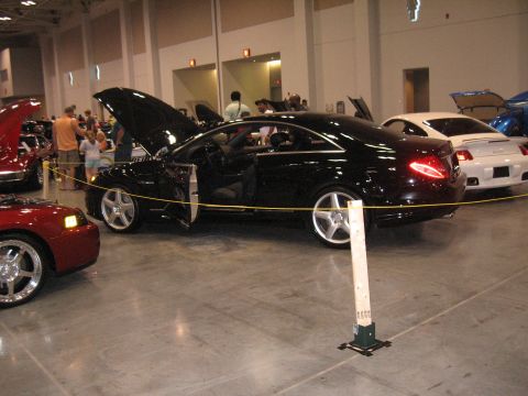 1968 Shelby GT500 - Indoor car show features a black coupe with its doors open, alongside other vehicles.
