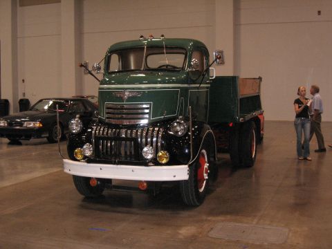 1968 Shelby GT500 - This vintage flatbed truck is on display indoors, with another car visible behind it.
