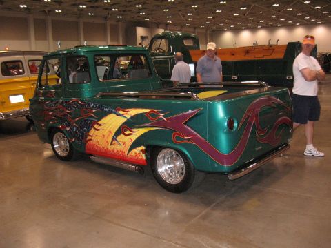 1968 Shelby GT500 - A custom pickup truck with elaborate flame and eagle graphics is displayed indoors, alongside other vehicles.