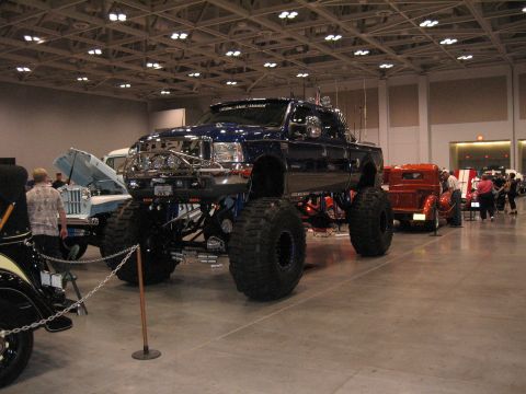 1968 Shelby GT500 - Custom lifted pickup truck at an indoor car show event.
