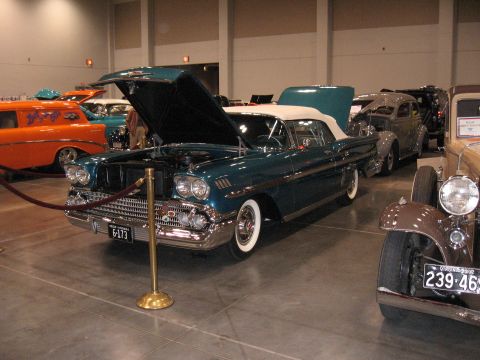 1968 Shelby GT500 - A teal 1958 convertible is displayed with its hood and trunk open at an indoor car show.