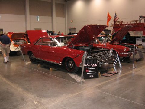 1968 Shelby GT500 - A red 1966 Ford Galaxie 500 coupe is displayed with its hood open at an indoor car show.