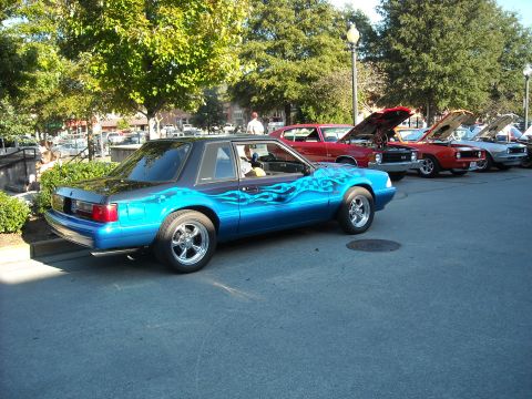 1979 Ford F-150 - A line of cars with hoods up at a car show, with a custom blue coupe in the foreground.