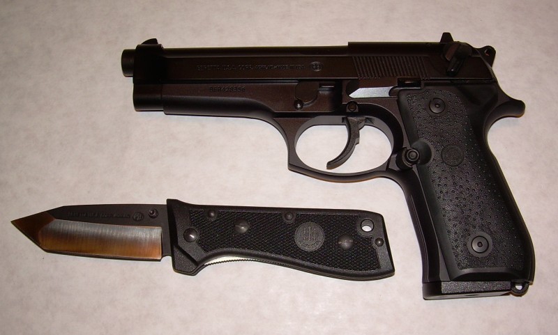 Beretta 92FS pistol and a black folding knife with a bronze blade