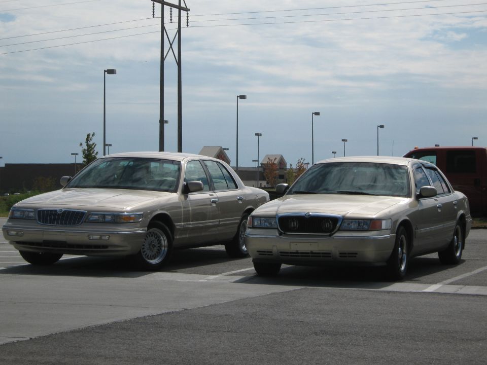 Two tan Mercury Grand Marquis sedans parked side-by-side in a lot