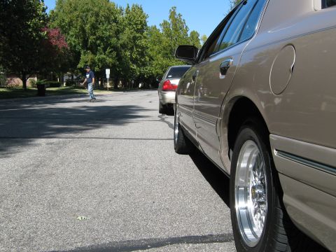 2000 Mercury Grand Marquis - A tan 2000 Mercury Grand Marquis is parked on a street, with another car behind it and a person in the distance.