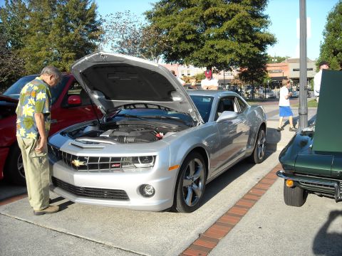 1979 Ford F-150 - A silver Chevrolet Camaro is displayed with its hood open at a car show, alongside other vehicles.