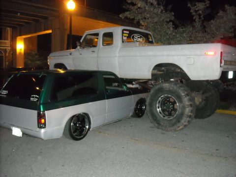 1979 Ford F-150 - A lifted 1979 Ford F-150 truck is parked over a lowered SUV at night.