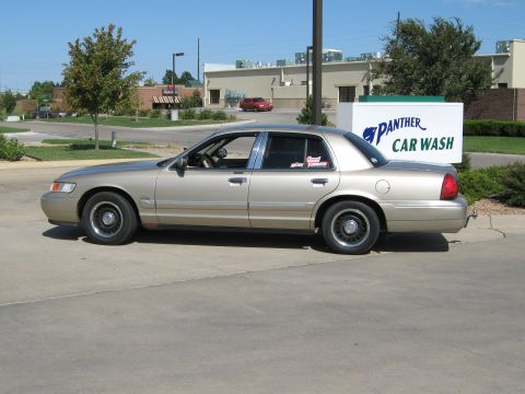 2000 Mercury Grand Marquis - A tan 2000 Mercury Grand Marquis sedan is parked in front of a car wash.