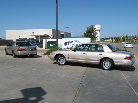 2000 Mercury Grand Marquis - Two Mercury Grand Marquis sedans are parked in a lot on a sunny day.