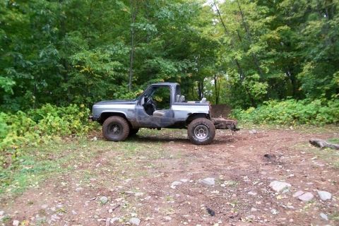 1988 Chevrolet Blazer - This modified SUV is parked on a dirt path surrounded by trees and foliage.
