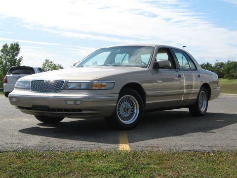2000 Mercury Grand Marquis - A tan 2000 Mercury Grand Marquis sedan is parked outdoors under a partly cloudy sky.