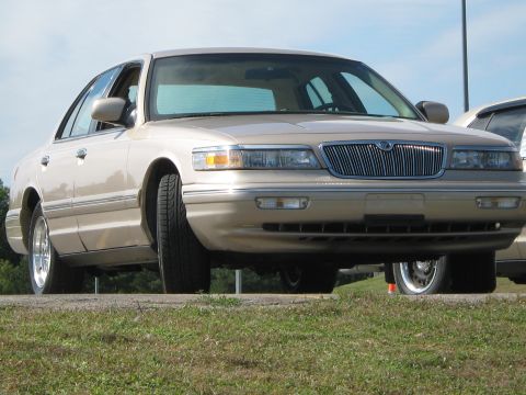 2000 Mercury Grand Marquis - A tan 2000 Mercury Grand Marquis is parked outdoors, viewed from the front with a clear sky above.