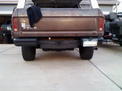 1979 Ford Bronco - The rear of a brown Ford Bronco is shown, with a spare tire carrier mounted below the bumper.