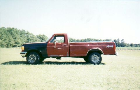 1987 Ford F-150 - A two-tone 1987 Ford F-150 pickup truck is seen from the side in an open field under a clear sky.
