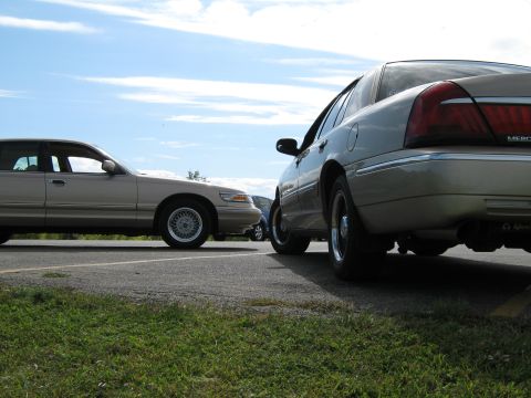 2000 Mercury Grand Marquis - Two Mercury Grand Marquis sedans are parked next to each other on a sunny day.