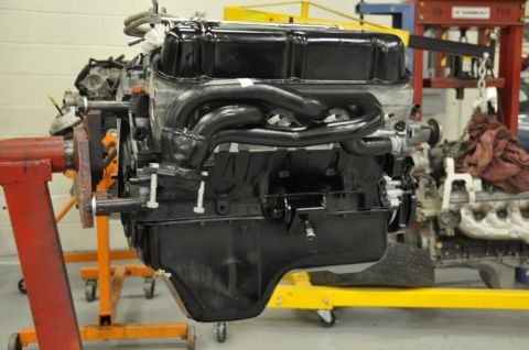 1996 Ford Bronco - Engine assembly with black headers mounted on a red engine stand, with another engine visible in the background.