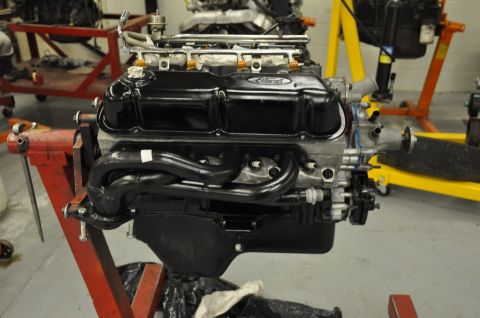 1996 Ford Bronco - A Ford V8 engine is mounted on a red engine stand in a workshop setting.