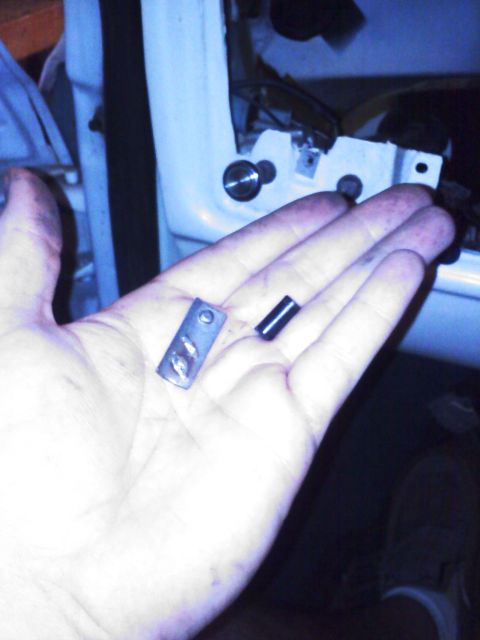 1977 Ford F-100 - Close-up of a hand holding two small metal automotive parts against a blurred background.