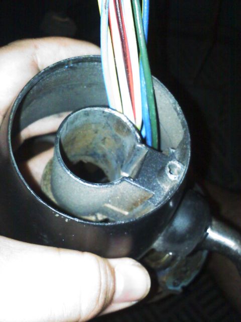 1977 Ford F-100 - A hand holds a steering column, revealing a bundle of wires ready for connection or repair.