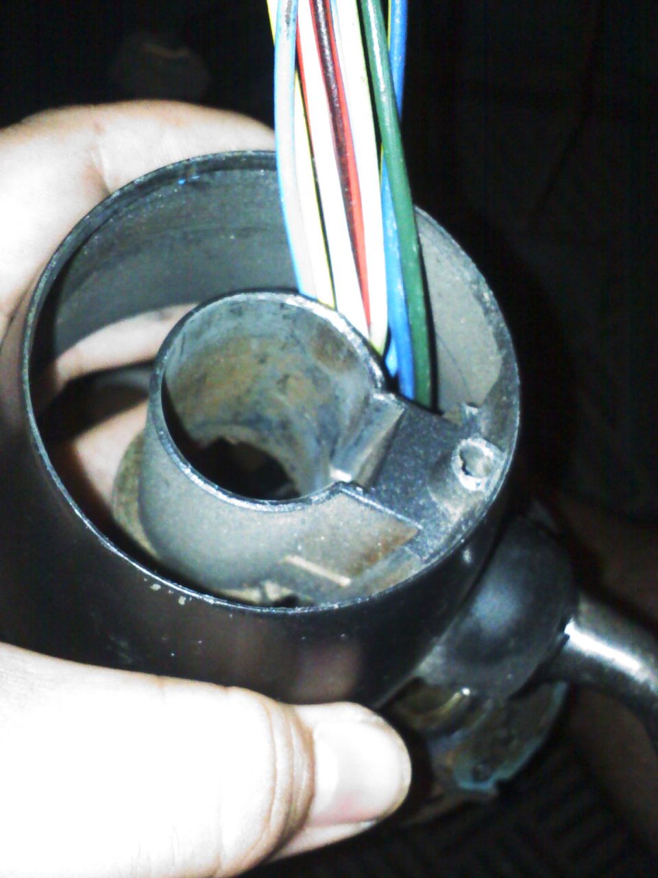 Close-up of a hand holding a steering column with a bundle of colorful wires emerging