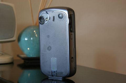 1992 Ford Taurus - A silver cell phone with a camera lens is shown from the side against a blurred background.