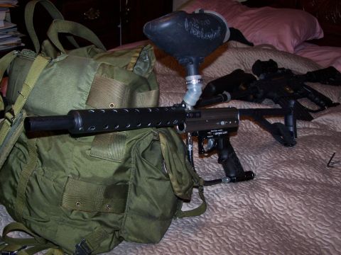 1986 Ford Bronco - A paintball gun and gear are laid out on a bed next to a green duffel bag.