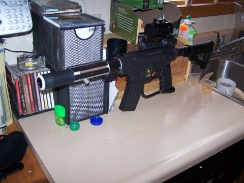 1986 Ford Bronco - Assault rifle with scope and extended barrel sits on a counter next to CDs and a phone.