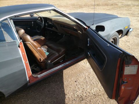 1975 Ford Ranchero - Interior view of a 1975 Ford Ranchero, showing the seats and dashboard with the driver's door ajar.