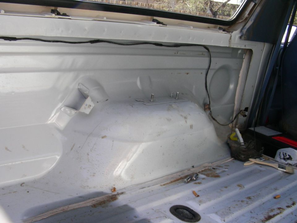 Freshly painted white rear cargo area interior with wheel tub and exposed studs