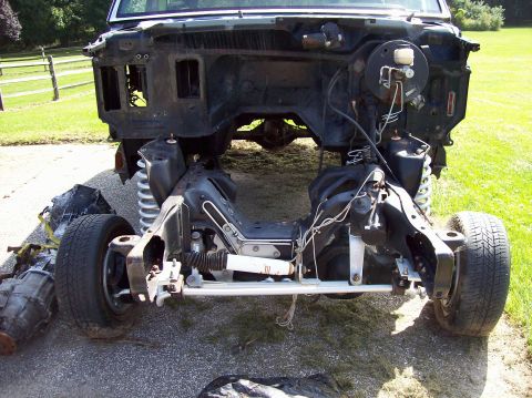 1990 Ford Bronco - Front end of a vehicle chassis undergoing disassembly, with suspension and drivetrain components exposed.
